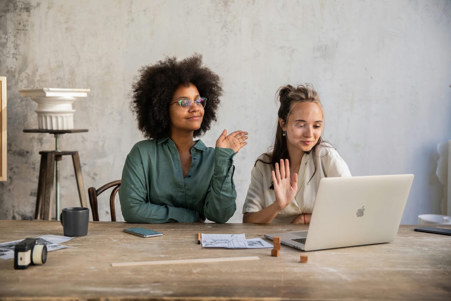 Two women waving at a laptop